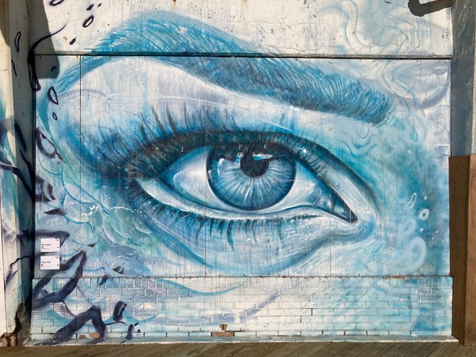 Mural of eye on brick wall.