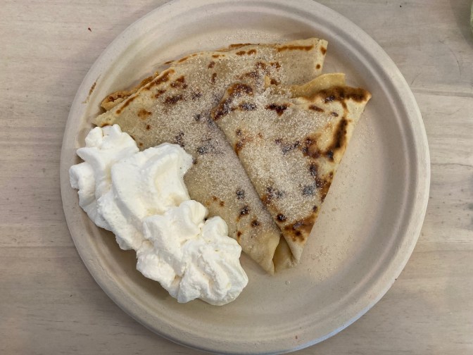 Butter and sugar crepe on paper plate, with side of whipped cream.