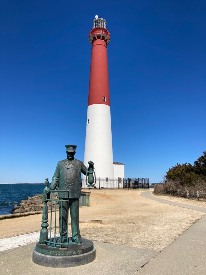 Barnegat Lighthouse, with statue of lighthouse keeper in foreground.