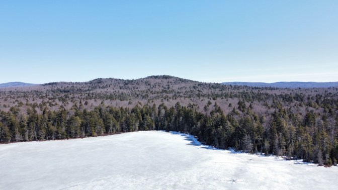View of Quiver Pond, and mountains in distance. Quiver Pond is covered in ice.