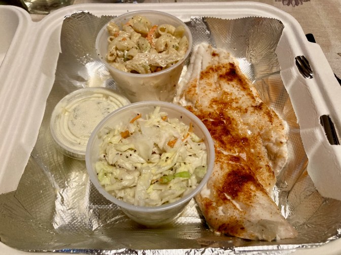 Broiled haddock in styrofoam container, with cup of coleslaw and cup of macaroni salad.