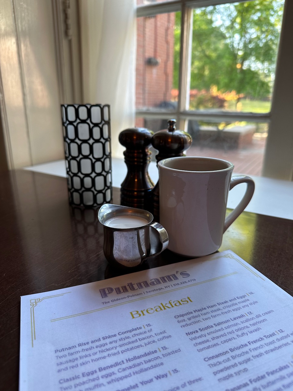 Table at restaurant with menu, coffee, and cup of cream.