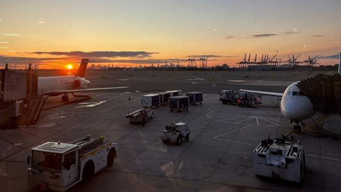 View of sunrise over New York City, with Newark airport tarmac in foreground.