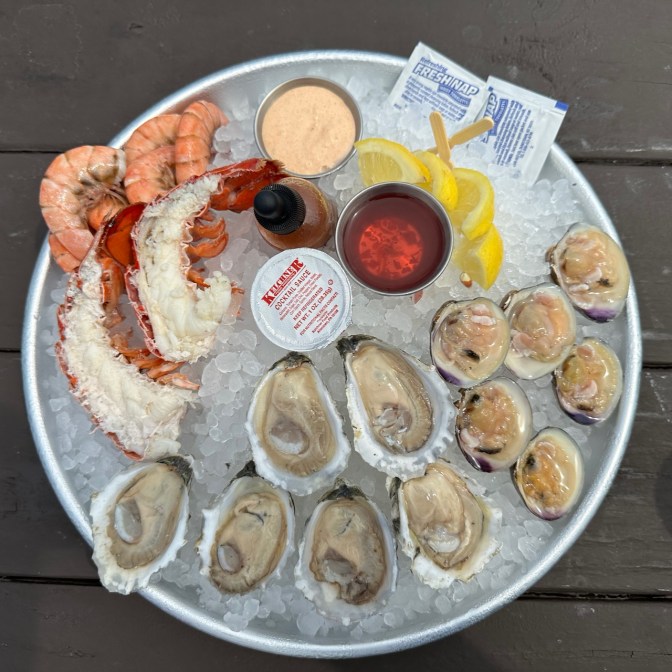 Ice-filled platter with clams, oysters, lobster tail, and steamed shrimp.