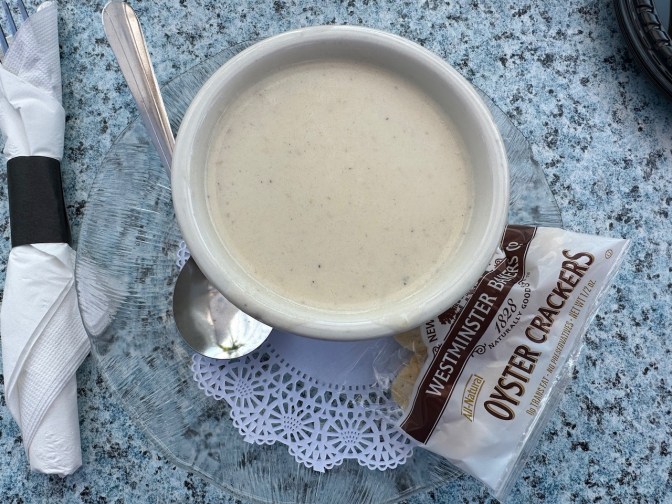 Cup of New England clam chowder with pack of oyster crackers on side.