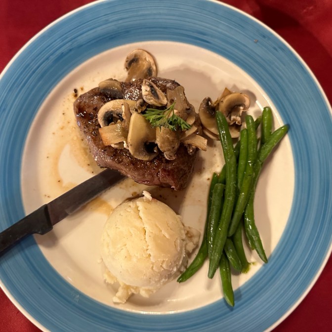 Steak, potatoes, and green beans on plate.