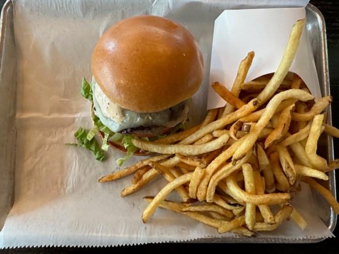 Cheeseburger and fries on metal tray.