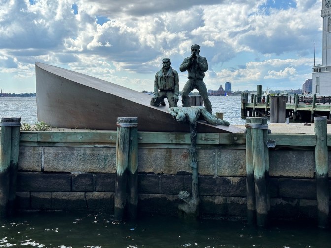 Sculpture of sinking whip, with three men on ship trying to reach man in water.