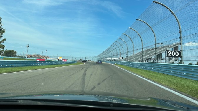 View of two cars on race track exiting corner.