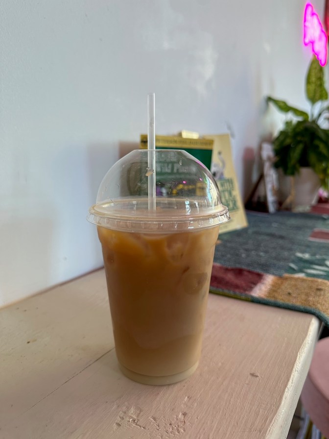 Iced oat milk latte on shelf.
