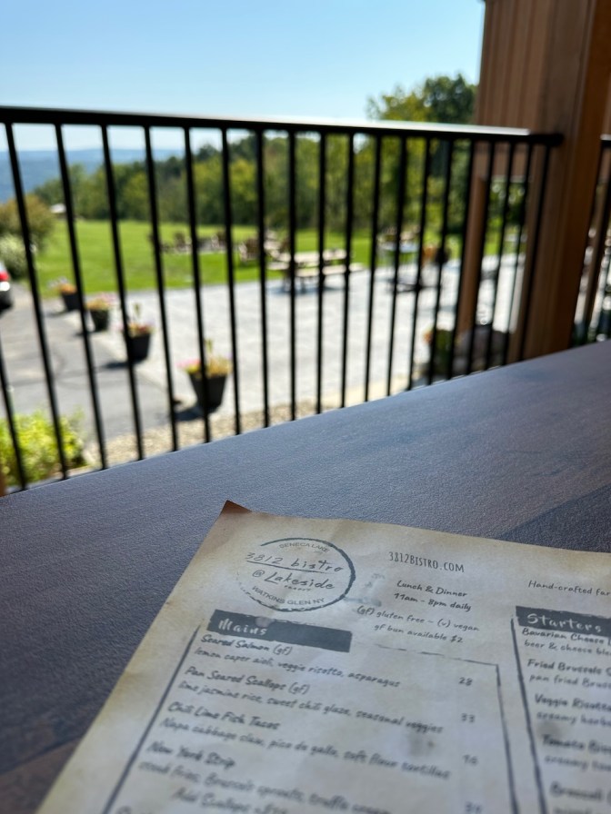 Deck of 3812 Bistro, with menu on table. Table overlooks back patio and Seneca Lake.