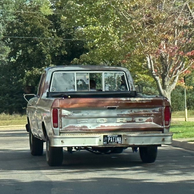 Rusty Ford pickup truck with license plate that says "Patina."