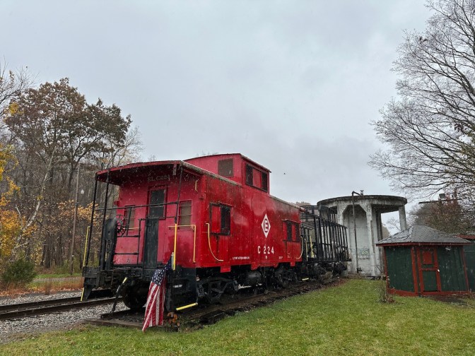 Two caboose cars on railroad track beside station.