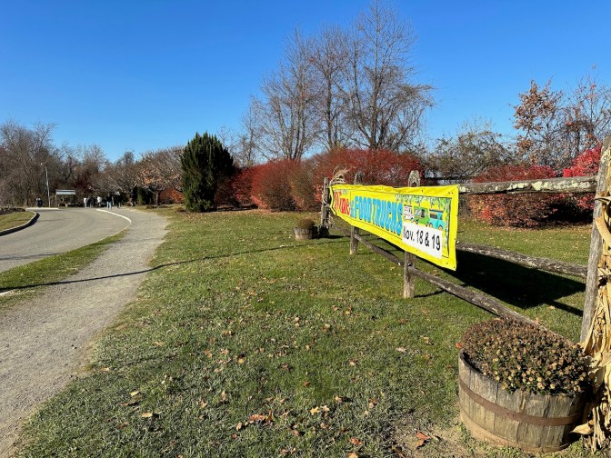Dirt path beside wooden fence, with banner for WINE AND FOOD TRUCKS NOV 18 AND 19.