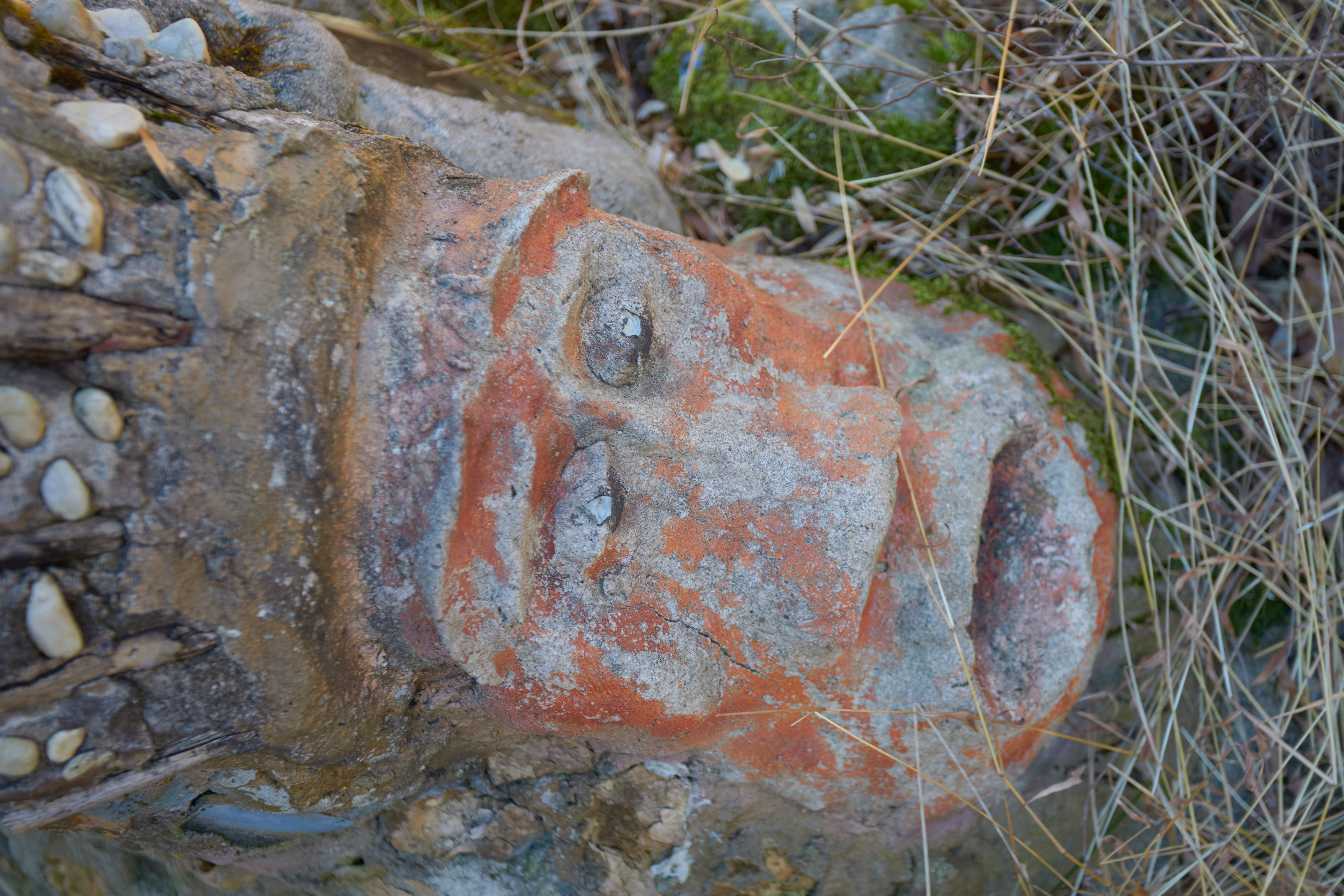 Sculpture of human face in ground.