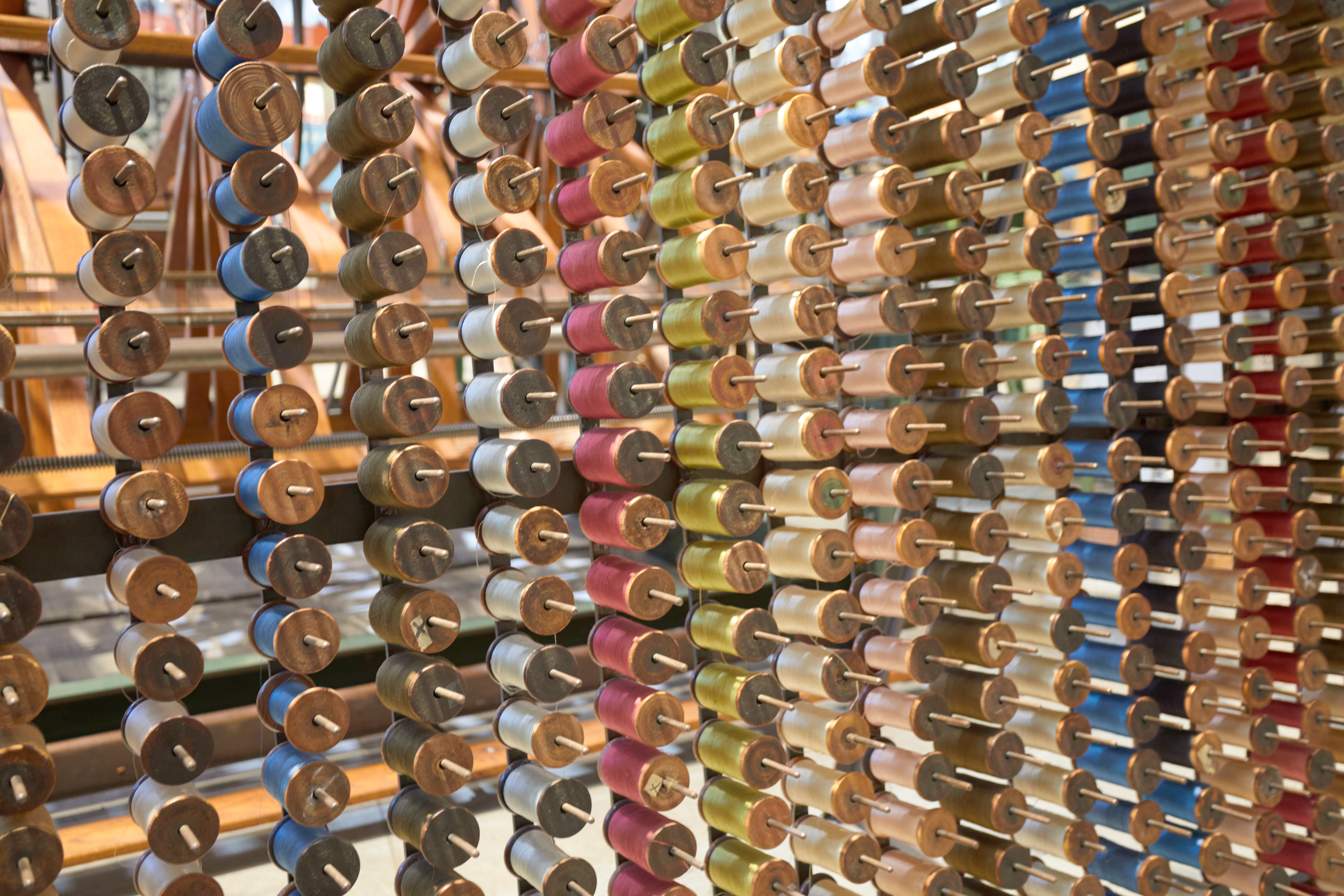 Spool creel with colored thread on bobbins.