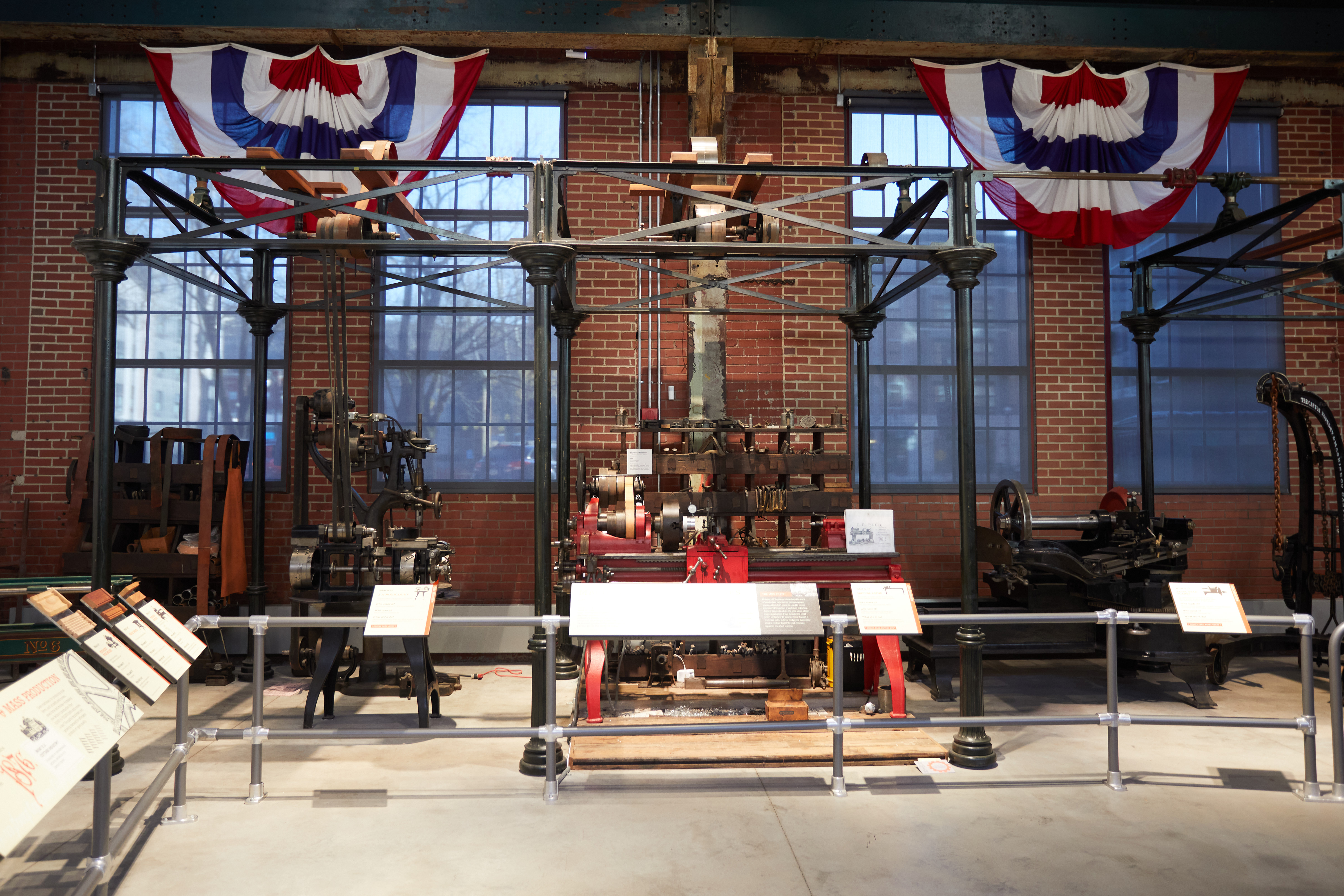 Displays of machines in front of brick wall. Red-white-and-blue bunting hangs from the ceiling.