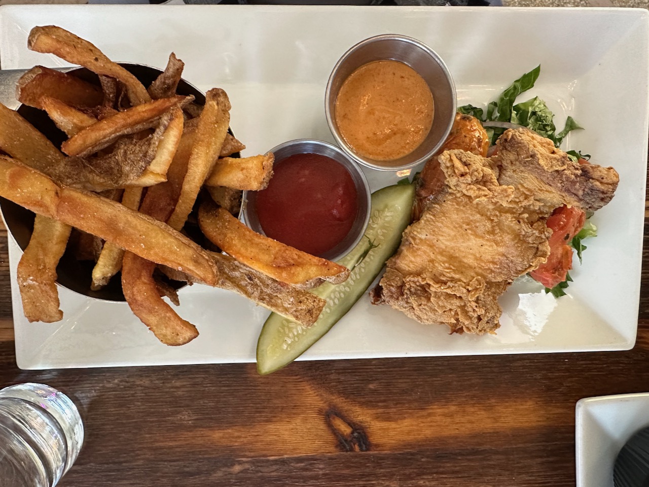 Crispy chicken, pickle, and fries on white plate.