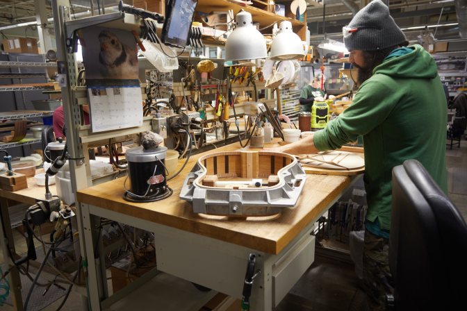 Man working on building guitar body in factory.
