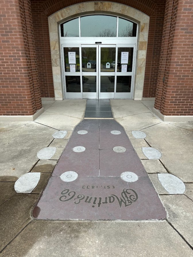 Sidewalk entrance to building, with guitar headstock design leading to front doors.