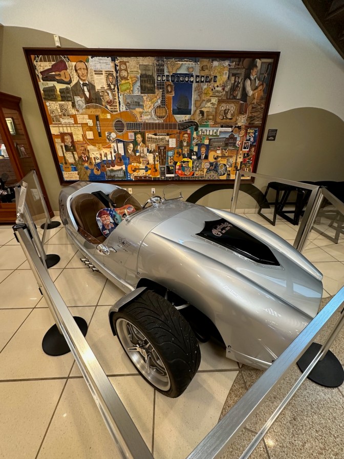 Custom three-wheeled motorcycle in front of mural of Martin Guitar history.