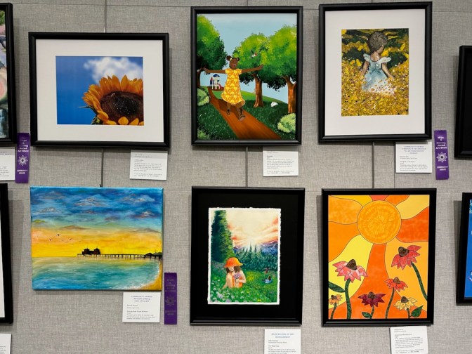 Six paintings and photographs on display on wall.