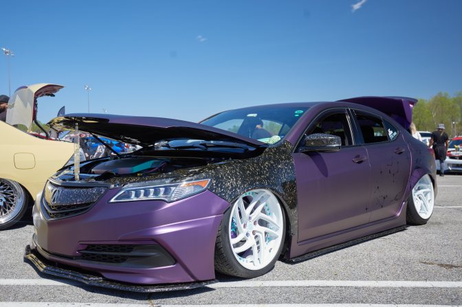 Acura TLX in purple wrap, with lowered stance, white wheels, and an open hood.