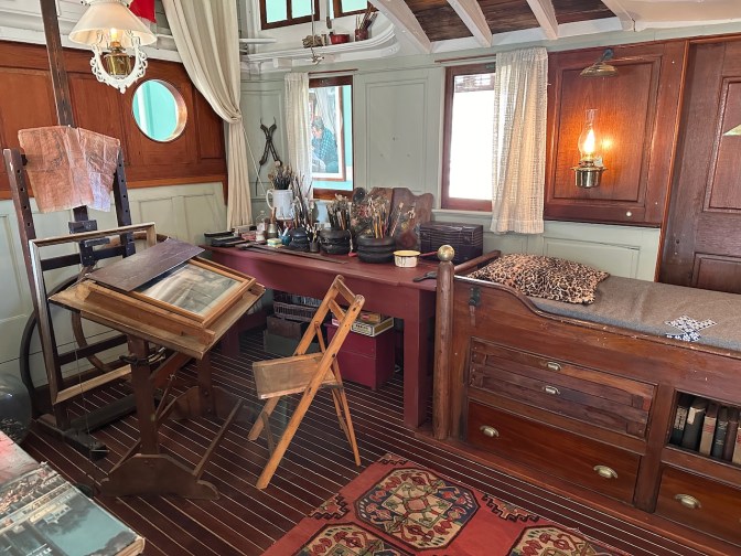 Interior of houseboat, with artists supplies and cabinets in view.