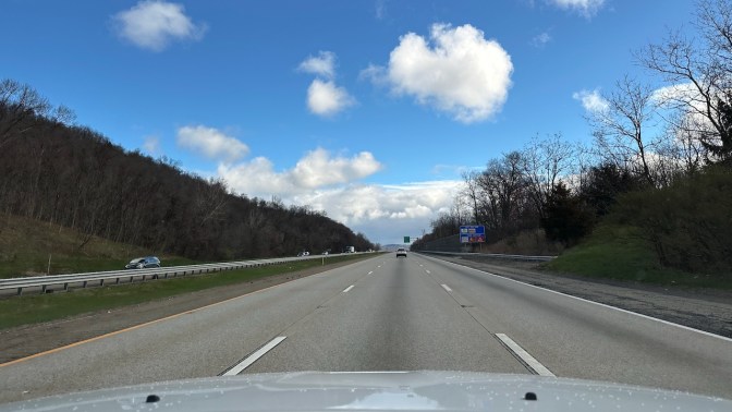 View of I-87 northbound under sunny skies with some clouds.