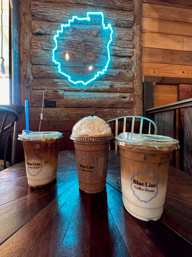 Three iced coffees on wooden table.