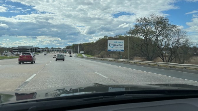 Sign by highway that reads WELCOME TO DELAWARE.