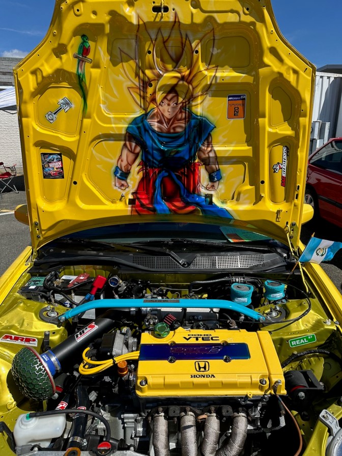 Yellow Honda Civic, with manga-themed character drawn on underside of Hood.