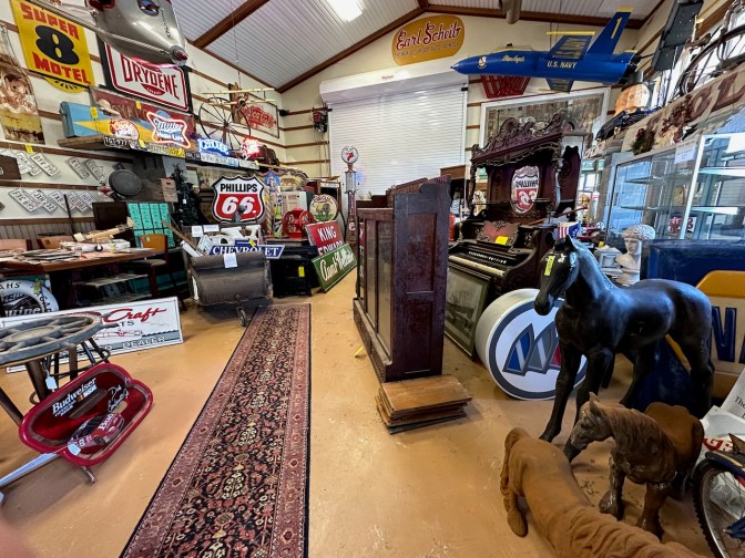Antique shop with business signs, pianos, toy animals, and other toys.