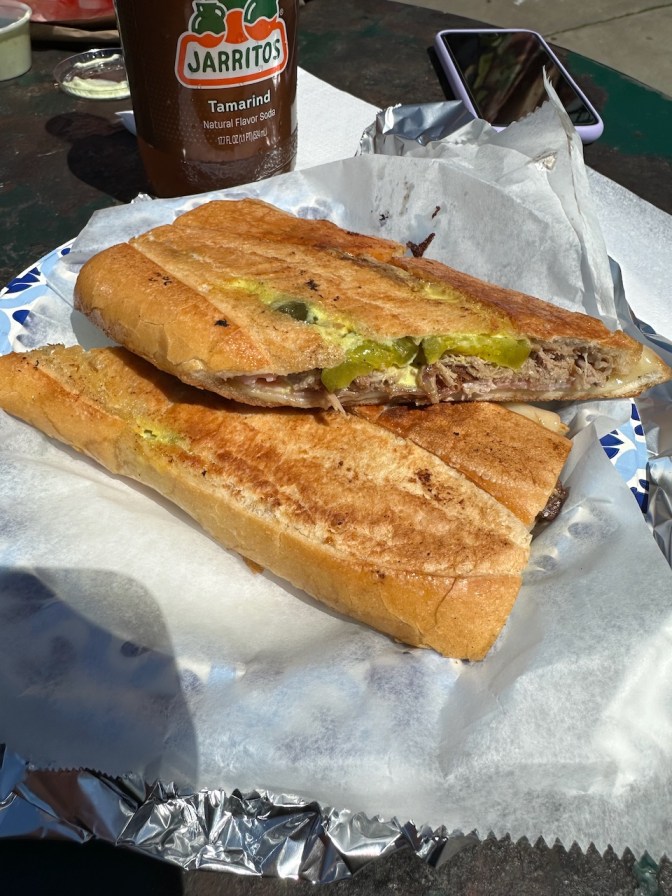 Cuban sandwich on wax paper, with tamarind Jarritos in the background.