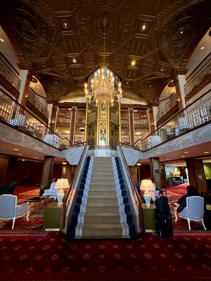Lobby of The Graduate Providence, with staircase and glass elevator in center.