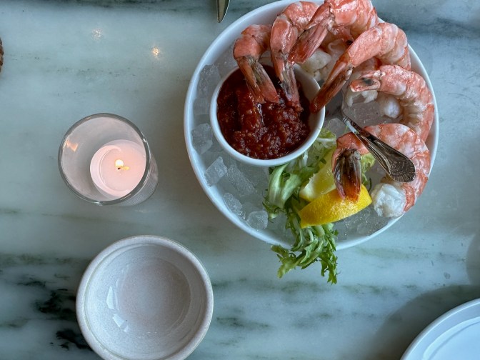 Shrimp cocktail and cocktail sauce in white bowl.