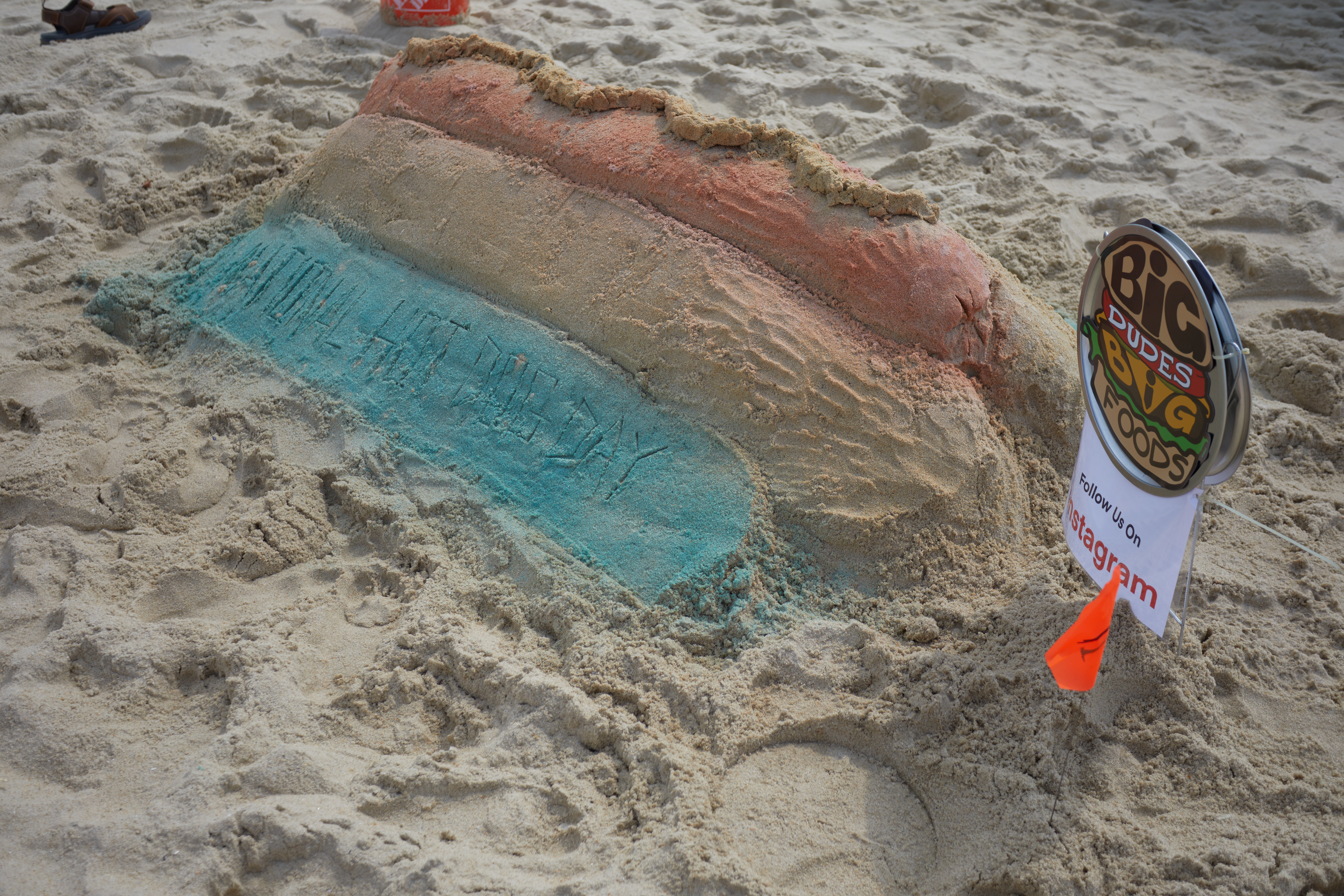 Hot dog sand art, with sign beside it that says BIG DUDES BIG FOODS.