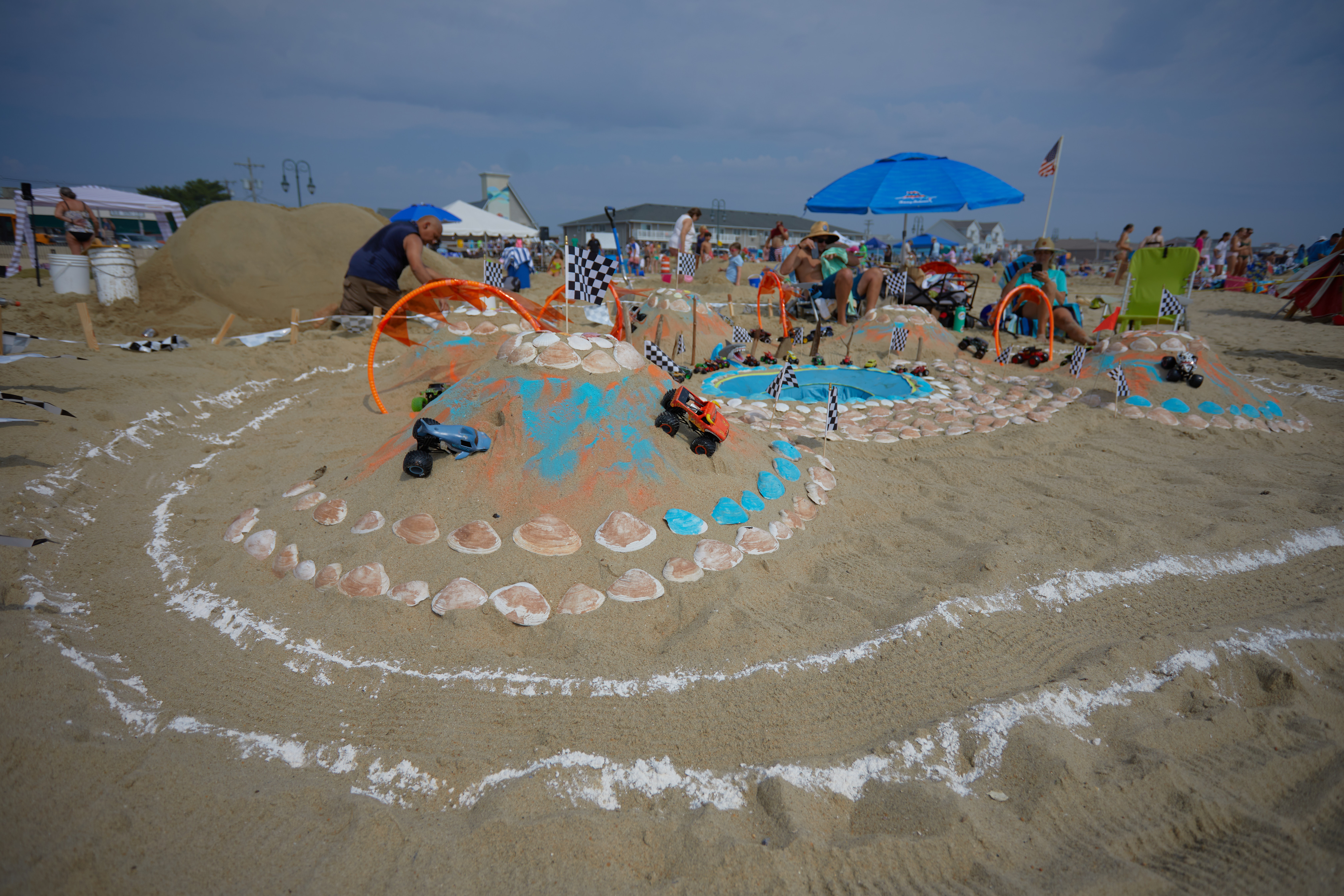 Obstacle course made of sand, with toy monster trucks maneuvering through the track.