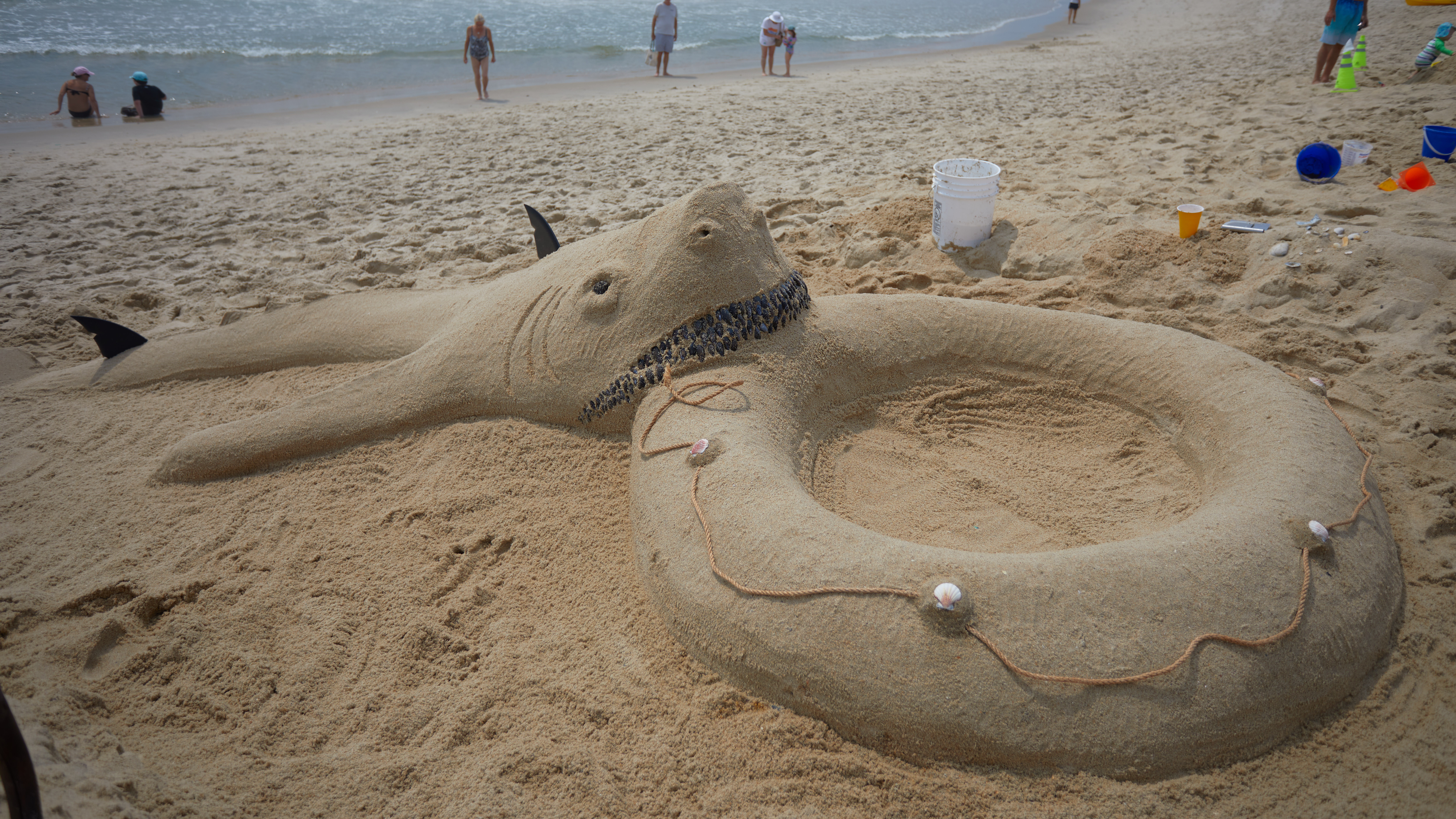 Sand sculpture of shark biting inner tube.