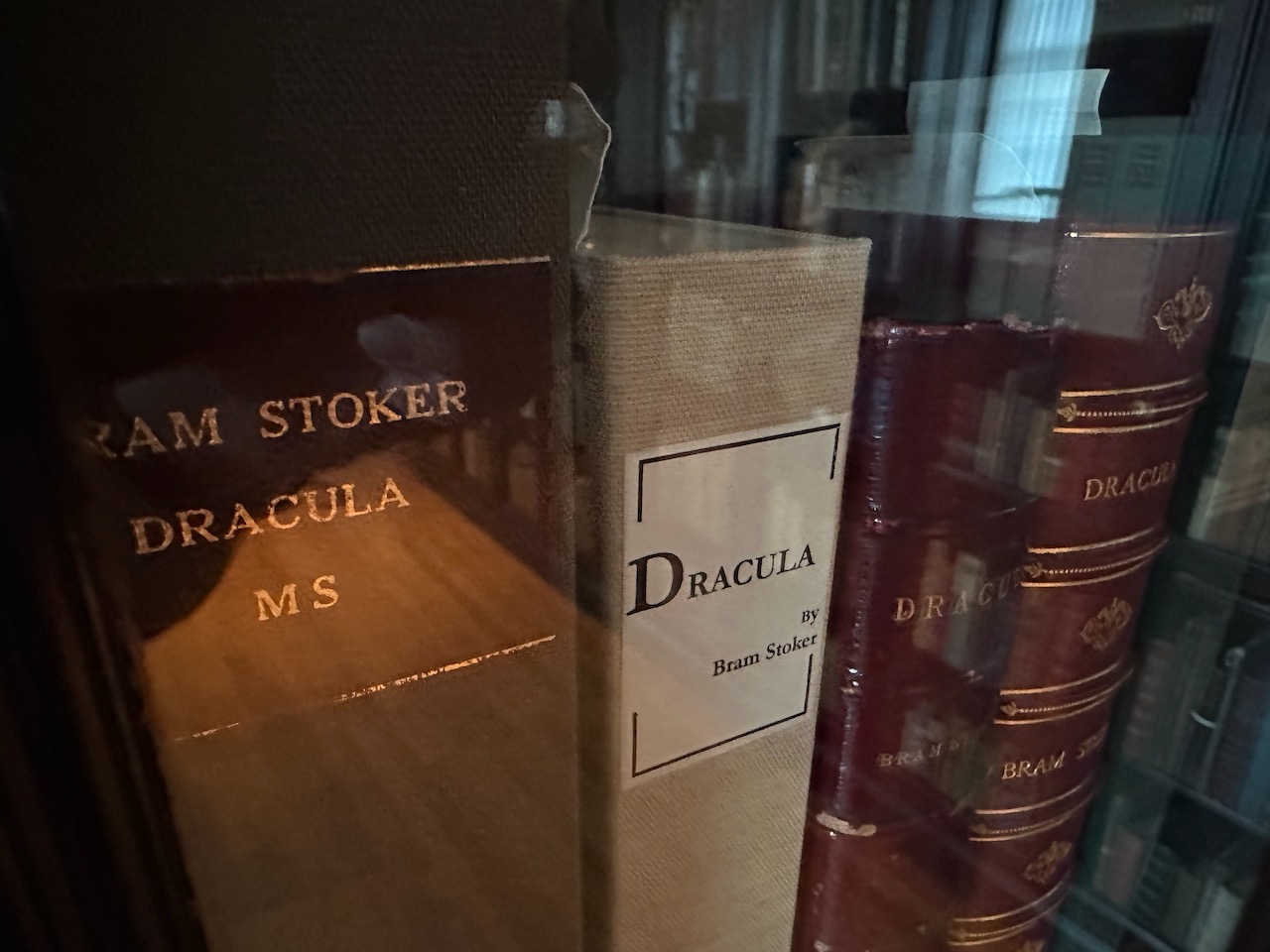 Several editions of Dracula by Bram Stoker on bookshelves, along with box containing original manuscript of Dracula.
