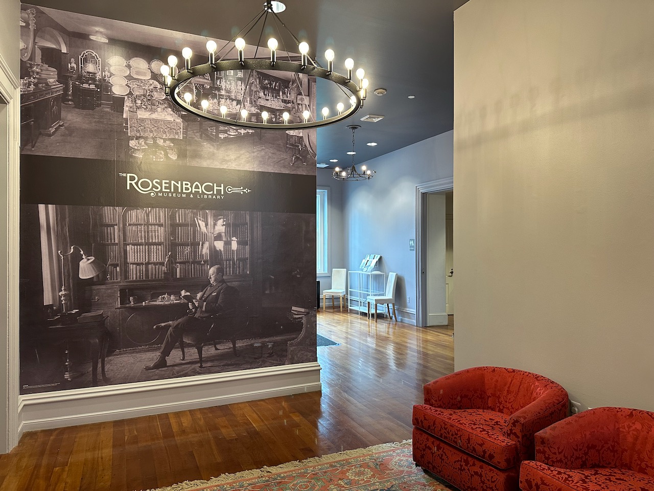Lobby of The Rosenbach Museum and Library. On one wall is a large photograph of a man sitting in a personal library.