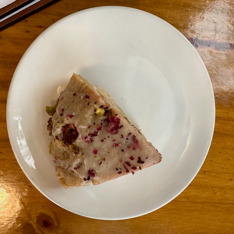Scone on white plate. Plate sits on wooden table.