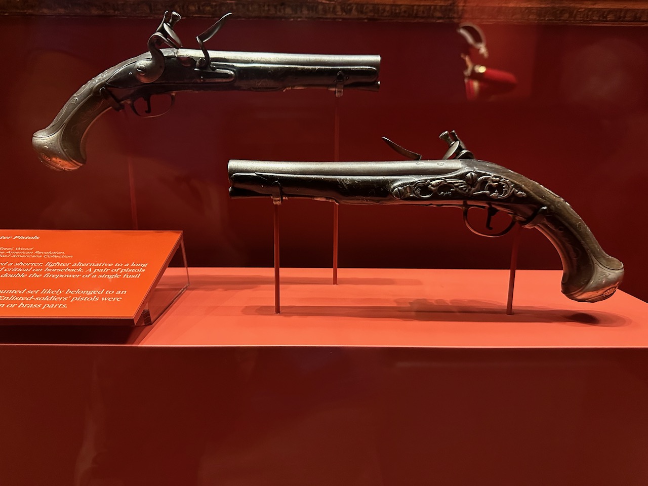 Two holster pistols on red display stand.