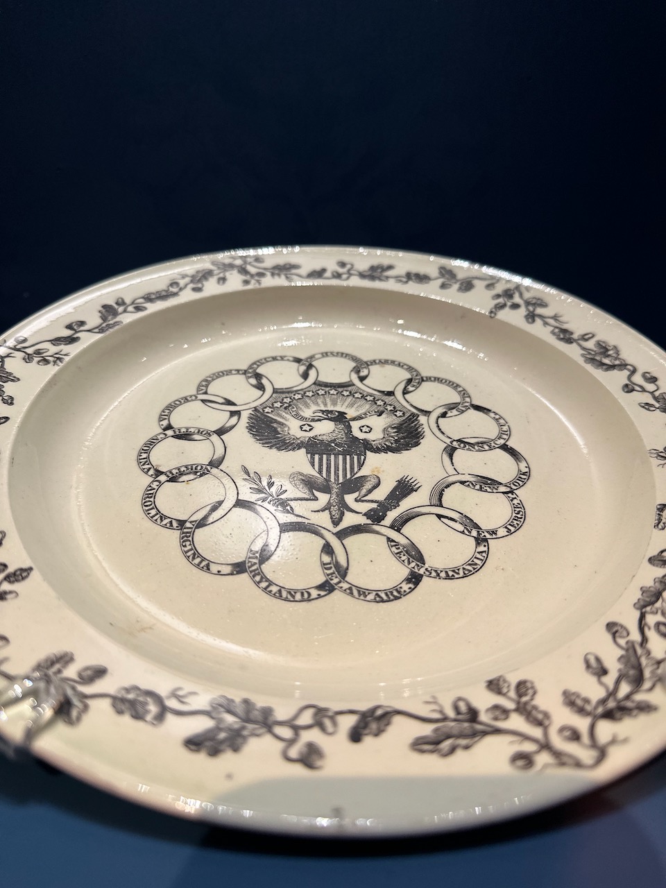 Plate with eagle emblem in middle, surrounded by chain with names of states.