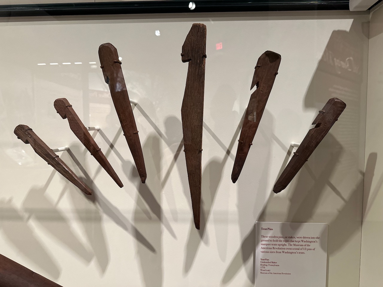 Display of six wooden tent pins.