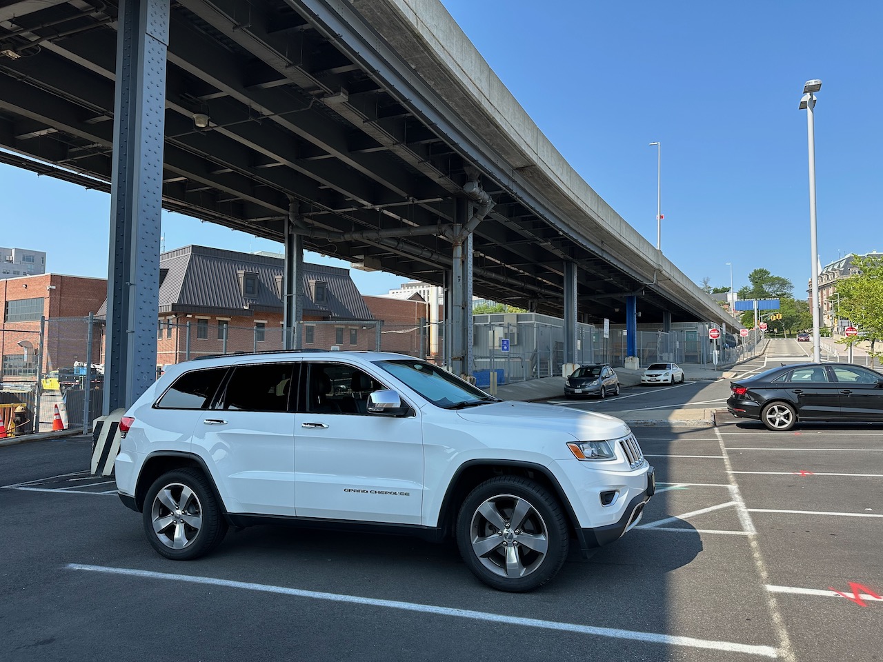 2014 Jeep Grand Cherokee, parked in parking lot. An elevated roadway is in background of photo.