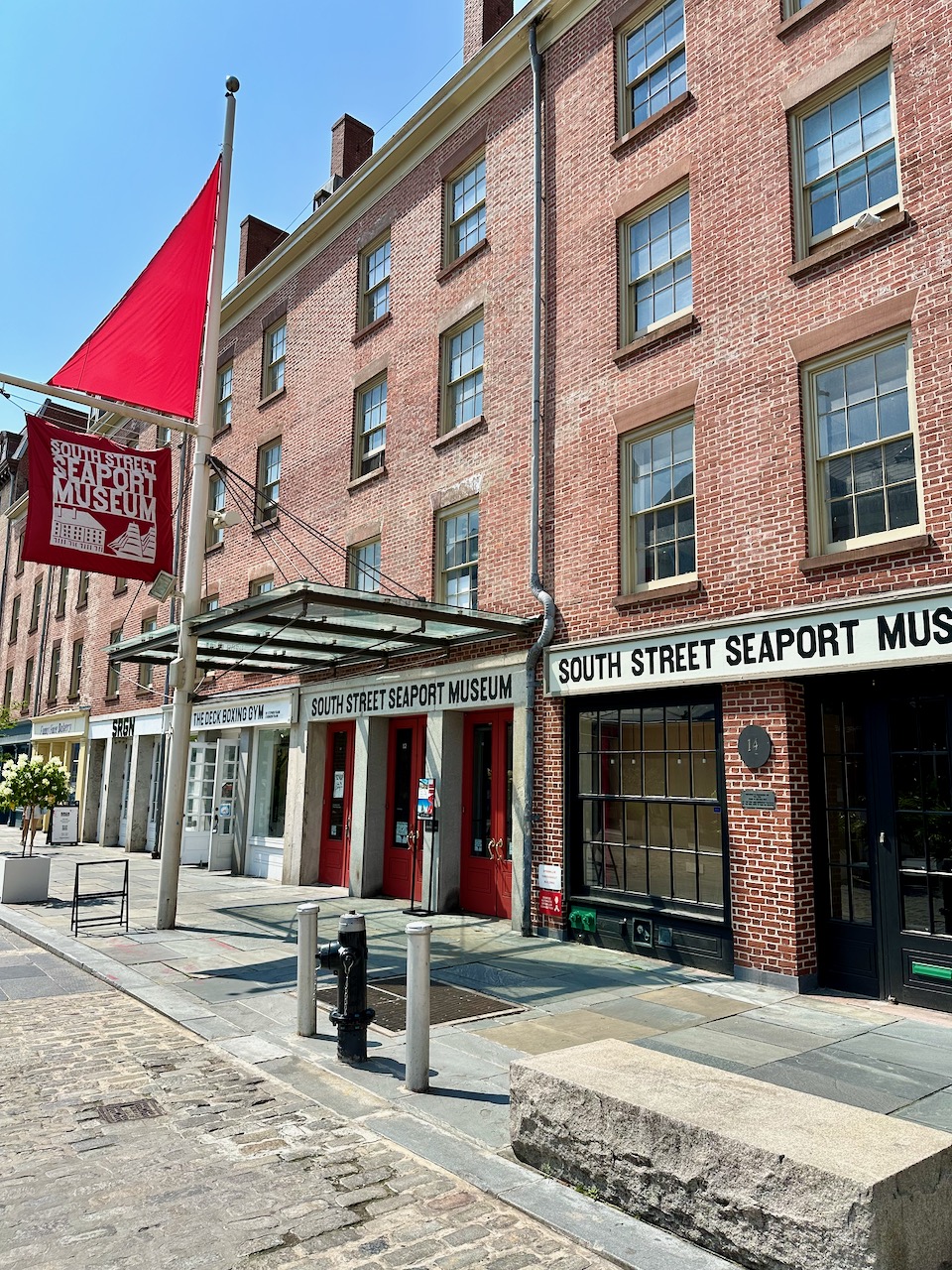 Exterior of South Street Seaport Museum - a four-story brick building on a brick street.