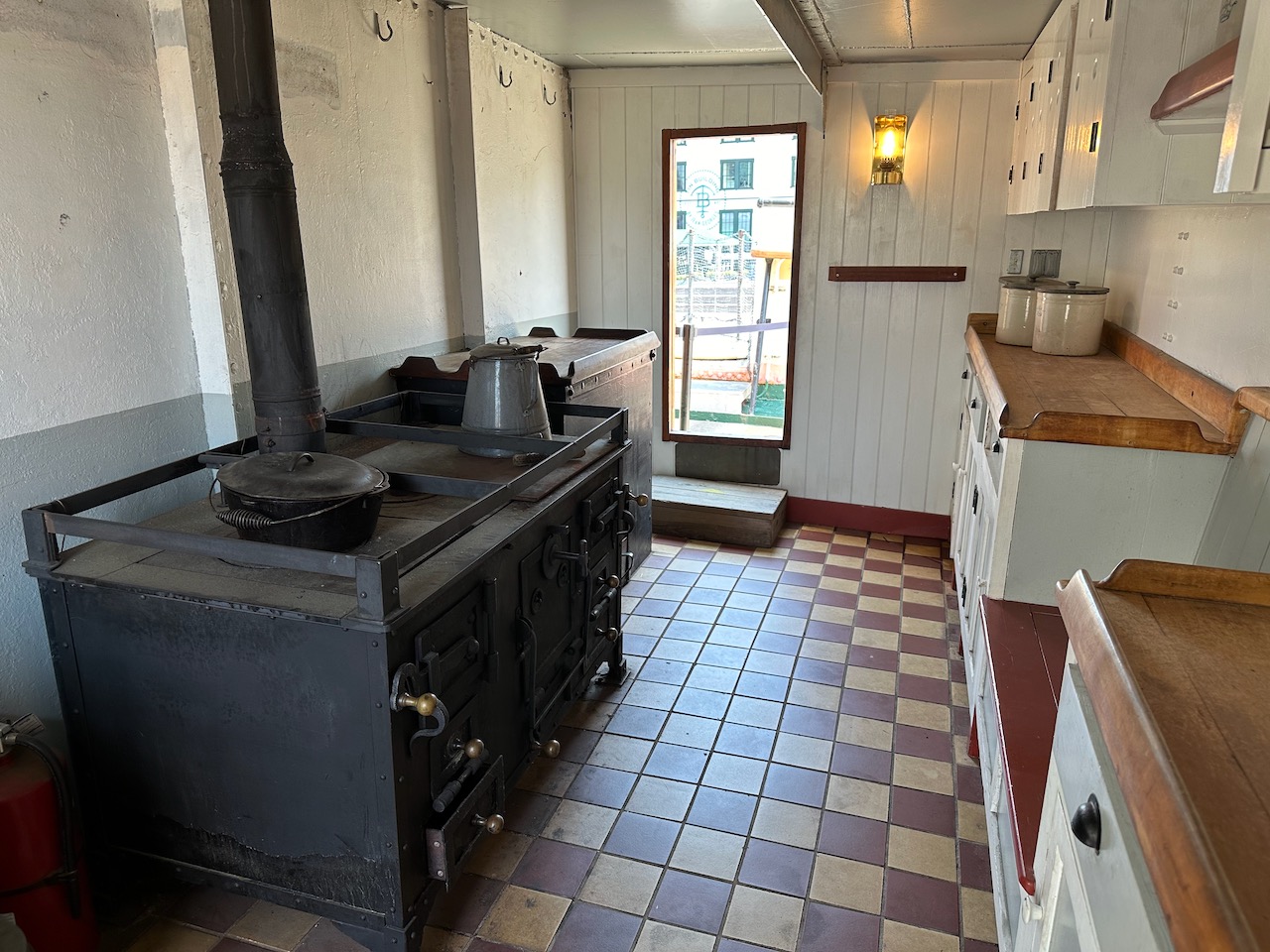 Ships galley, with large iron stove along forward wall of room.