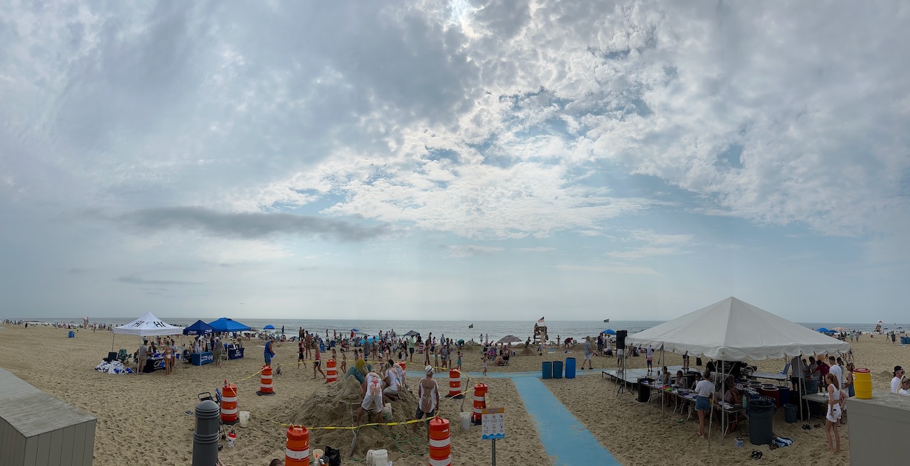 Panorama of sand castle contest on beach.