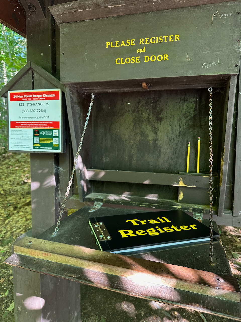 Trail register book on folding shelf at trail head.